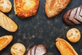 A group of varied bread on a dark rustic surface, a place for your text. Frame of fresh bread. View from above. Royalty Free Stock Photo