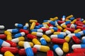 Colorful medicine capsules on dark background, horizontal