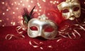 A group of Venetian or Mardi Gras masks on a dark, glittery surface with a bokeh light effect in the background.