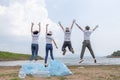 Group of volunteers cheerful success jumping together and arms raised with rubbish bags foreground. clean up garbage in tourist Royalty Free Stock Photo