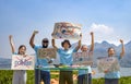 group of volunteers holding environmental campaign signs standing by the river