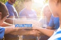 Group of volunteers joining hands together outdoors