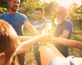 Group of volunteers joining hands together on sunny day