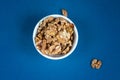 Group of wallnuts in a bowl is on a blue background, healthy food concept