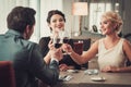 Group of wealthy people clinking glasses of red wine in restaurant