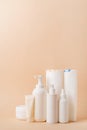 Group of white blank packaging tubes and containers for cosmetics on beige natural color background, mockup design, eco