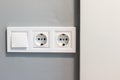 Group of white european electrical outlets and a switch located on a gray wall