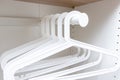 Group of white plastic empty handgers in a wardrobe, hanging on a metal tube Royalty Free Stock Photo
