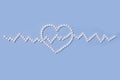 Group of white round pills forms heart figure next to heart rhythms from white pills on a blue background. Royalty Free Stock Photo