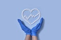 Group of white round pills forms heart figure next to heart rhythms from white pills and hands in medical gloves on a Royalty Free Stock Photo