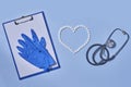 Group of white round pills forms heart figure from white pills, notebook, blue gloves and stethoscopen on blue