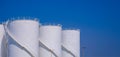 Group of white storage fuel tanks in petroleum industrial area against blue clear sky background in panoramic view Royalty Free Stock Photo