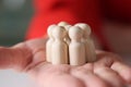 Group of white wooden figures standing on palm of woman