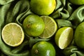 Group of whole and cut fresh limes on green satin