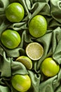 Group of whole and cut fresh limes on green satin