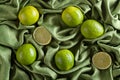 Group of whole and cut fresh limes on green satin