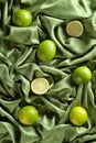 Group of whole and cut fresh limes on green satin