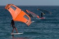 A group is wing foiling using handheld inflatable wings and hydrofoil surfboards in a blue ocean Royalty Free Stock Photo