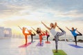 A group of women doing yoga at sunrise near the sea