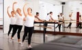 Group of women perform the battement tendu movement, standing in a ballet stance near the barre Royalty Free Stock Photo
