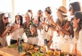 Group of women in friendship enjoying a party on the terrace toasting with red wine. Vegan food on the wooden table. Simplicity Royalty Free Stock Photo