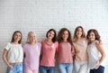 Group of women with silk ribbons near brick wall.