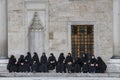 A group of women sitting in the courtyard of the Blue Mosque in Istanbul.