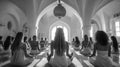 A group of women are sitting on yoga mats in a blackandwhite themed room