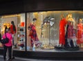 Group of women standing in front of a storefront with mannequins wearing colorful clothes