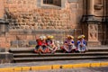 Group of women in traditional Peruvian dresses, sitting on the street