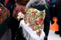 A group of women wearing bright floral headscarves draped over a fur-collared coat