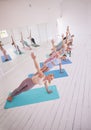 Group of women in yoga class together. Young women in side plank on yoga mats. Group of strong women balance in pilates