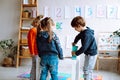 Group of wonderful children preschoolers studying playing in bright classroom. Pupils standing around white table.