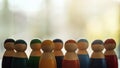 Group of wooden figurines in different colors standing in a row for the concepts of diversity and business