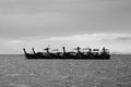 Group of wooden long tail boat floating on sea with raining cloud background in black and white tone or monochrome. Royalty Free Stock Photo