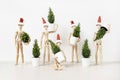 Group of wooden mannequins in Santa Claus hats holding Christmas trees