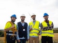 Group of workers and engineers in a field of windmills looking at camera smiling. Wind energy, renewable energy
