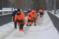 A group of workers remove snow from a sidewalk on a footbridge over a river during heavy snow on a winter day. Royalty Free Stock Photo