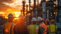 Group of workers in safety gear overseeing an industrial site at sunset, emphasizing teamwork and construction Royalty Free Stock Photo