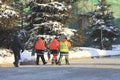 Group of workers with shovels in overalls walking on winter snow-covered street in the city