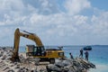 Group of workers using excavator at construction site on shore of ocean Royalty Free Stock Photo