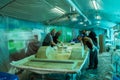 A group of workers wearing safety masks glue the fiberglass hull of a pedal catamaran. Construction of a fiberglass boat Royalty Free Stock Photo