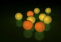 Group of yellow and orange golf balls, glowing on a reflecting surface