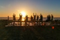 Group doing yoga exercises on the beach at sunset