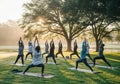 Group yoga class practicing sun salutations outdoors in a park Royalty Free Stock Photo