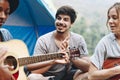 Group of young adult friends in camp site playing guitar Royalty Free Stock Photo