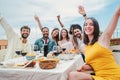 Group of young adult friends having fun and laughing on a dinner party rooftop. Happy multiracial people celebrating a Royalty Free Stock Photo