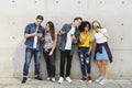 Group of young adults outdoors using smartphones together and ch Royalty Free Stock Photo