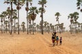 Group of young African walking with buckets through the palm trees