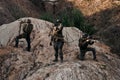 Group of young army soldier with rifles in combat uniforms in mountains